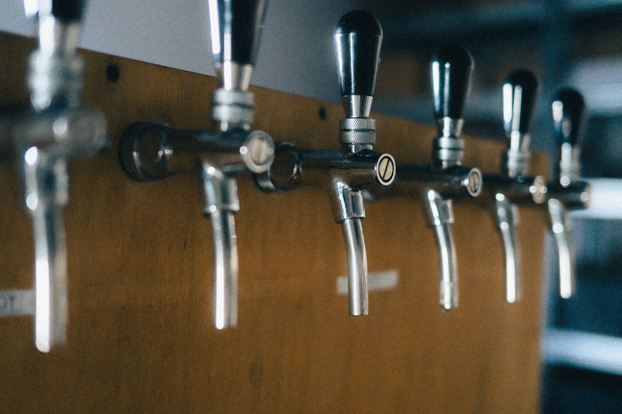Detail of shiny beer tap handles in a dimly lit bar setting.